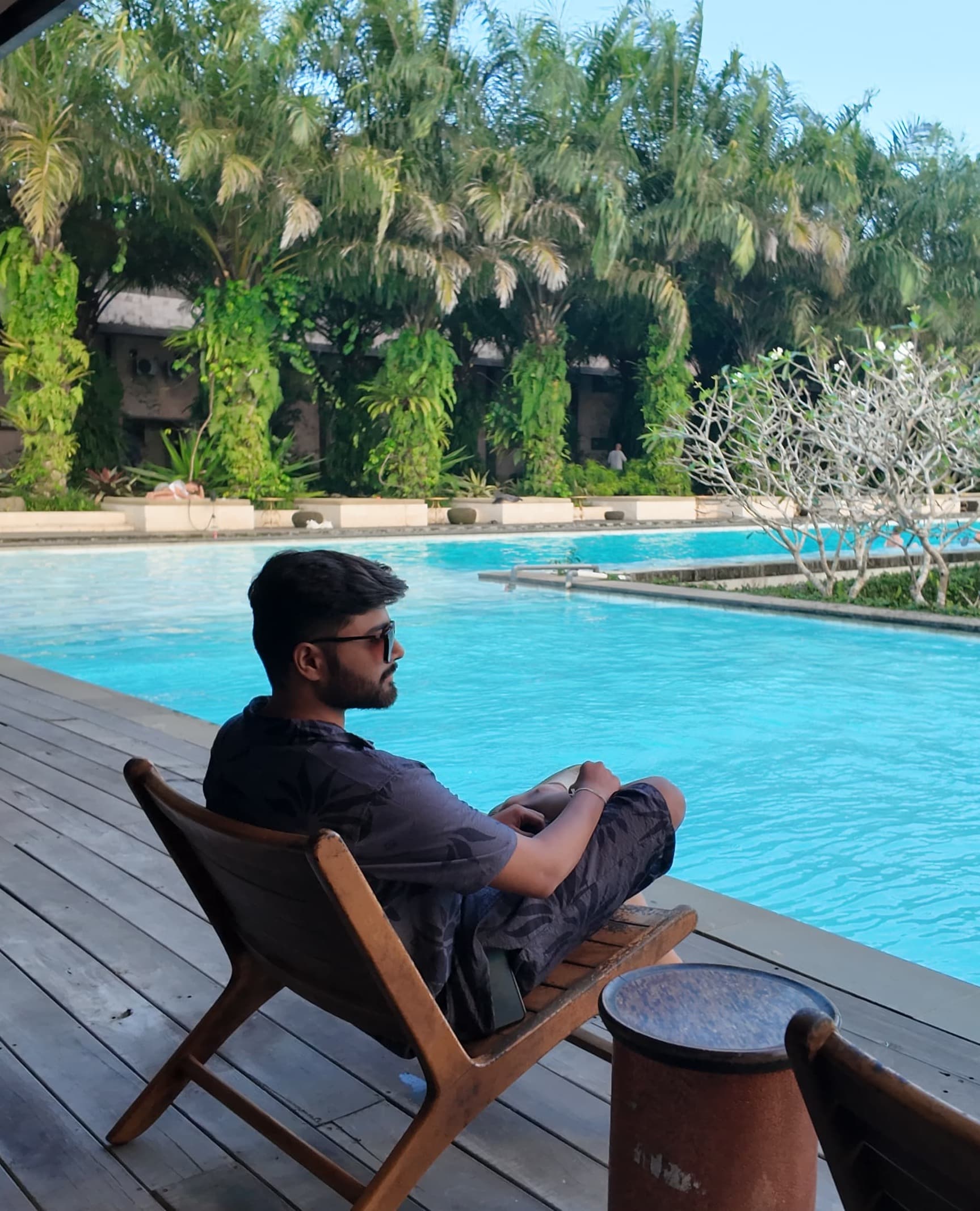 Dhruvin sitting by the swimming pool at a resort in Bali